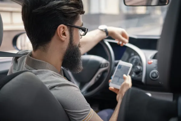 muž používající mobilní telefon během řízení